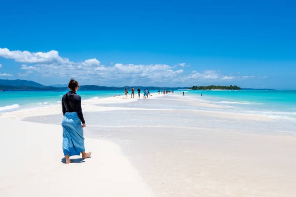 A visitor walking across the white sandbar at Nosy Iranja